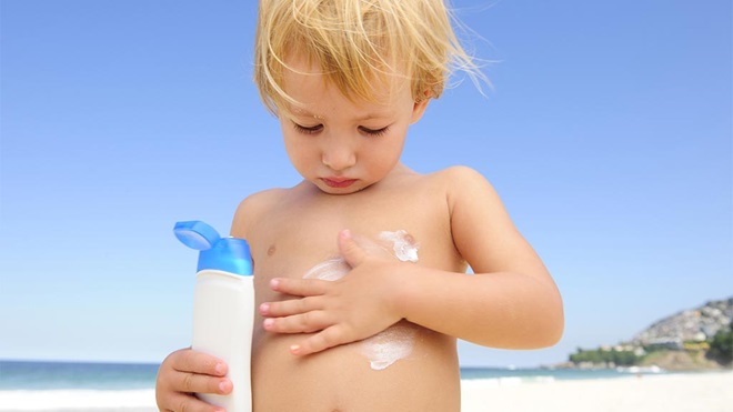 boy applying sunscreen to chest